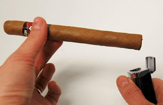 ženské ruky držiace cigaru a cigarový zapaľovač
