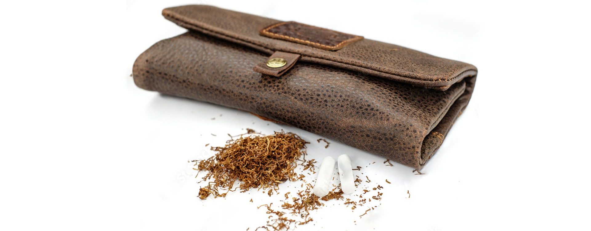 Kožené puzdro na tabak uzavreté na bielom pozadí, rozsypaný tabak a filtre