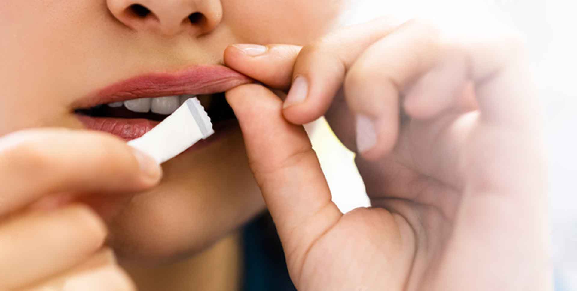 Žuvací tabak - snus: mladá žena si vkladá do úst vrecúško so žuvacím tabakom - detail